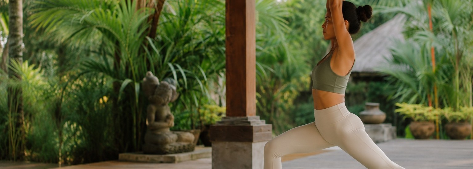 Woman flowing through a strength-building standing yoga sequence in a bright Bali pavilion